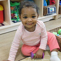 Toddler sitting on classroom floor during playtime