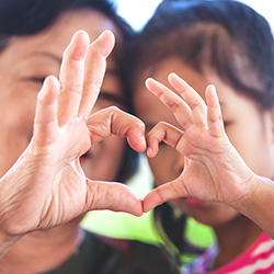 Teacher and child making heart symbol with each of their hands
