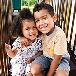 Boy and girl with arms around each other on playset