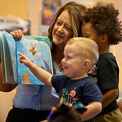 Teacher reading a book to two young boys