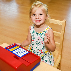 Girl playing with pretend cash register on table