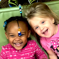 Two girls sitting in chair laughing