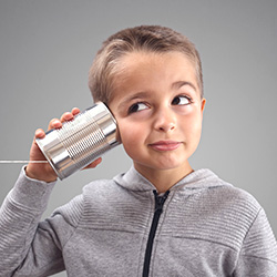 Young boy holding tin can to his ear