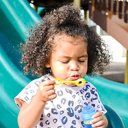 Little girl blowing bubbles on a slide